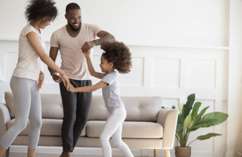 happy family of three dancing around living room